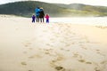 Happy young family is walking on sandy beach and ocean Royalty Free Stock Photo